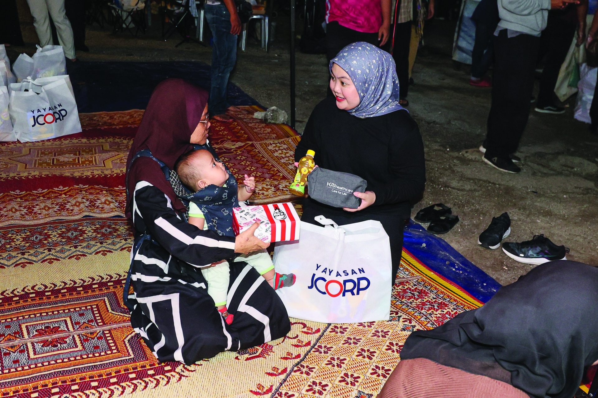 salah seorang anggota pekerja yayasan jcorp beramah mesra bersama penerima sumbangan